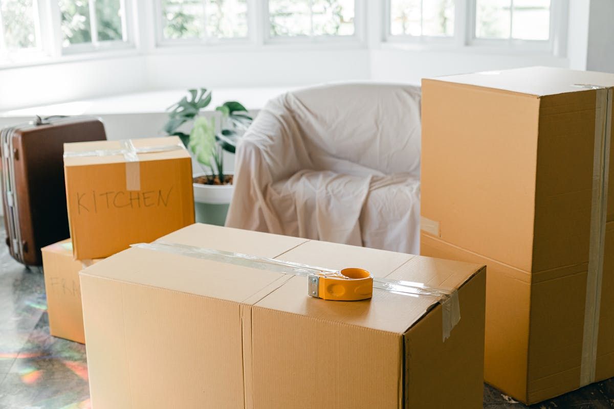 Stacked cardboard moving boxes in a sunlit room during relocation