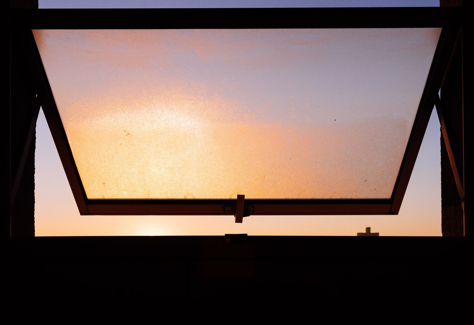 Open awning window with sunlight illuminating the glass and frame